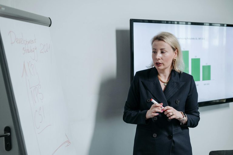 A professional businesswoman presenting a development strategy using charts and graphs in an office setting.